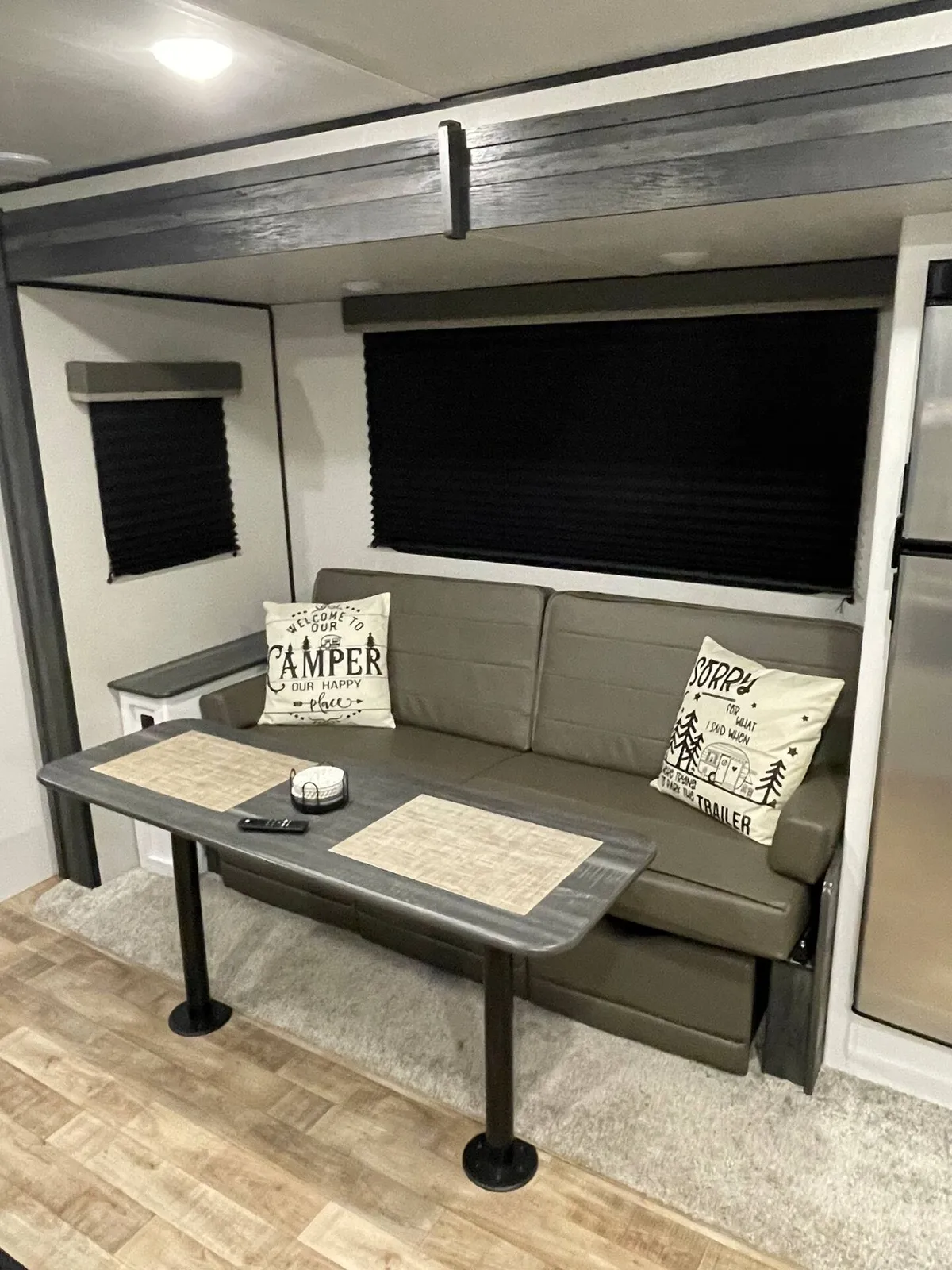 This image presents a cozy RV interior with a sofa, dining table, and plush decorative pillows. The area exudes a sense of warmth and togetherness, evoking scenes of relaxation, dining, and evenings spent playing games or sharing stories.